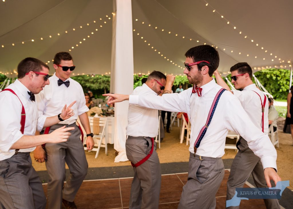 Groom groomsmen dance in bowties and suspenders