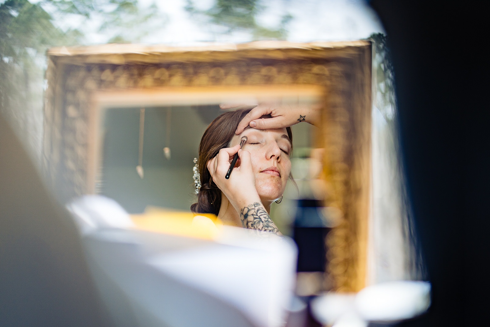 Photograph of a mirror with a reflection of a bride having her makeup done by Raleigh wedding photographer