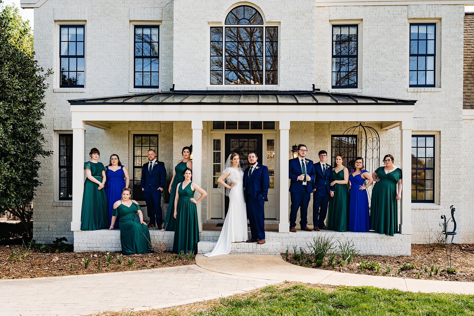 Wedding party poses for a portrait at The Meadows Raleigh in green and blue dresses and blue suits