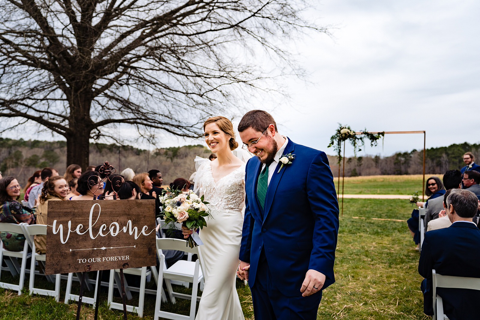 Bride and groom smile happily as the recess down the aisle at their Meadows Raleigh wedding ceremony