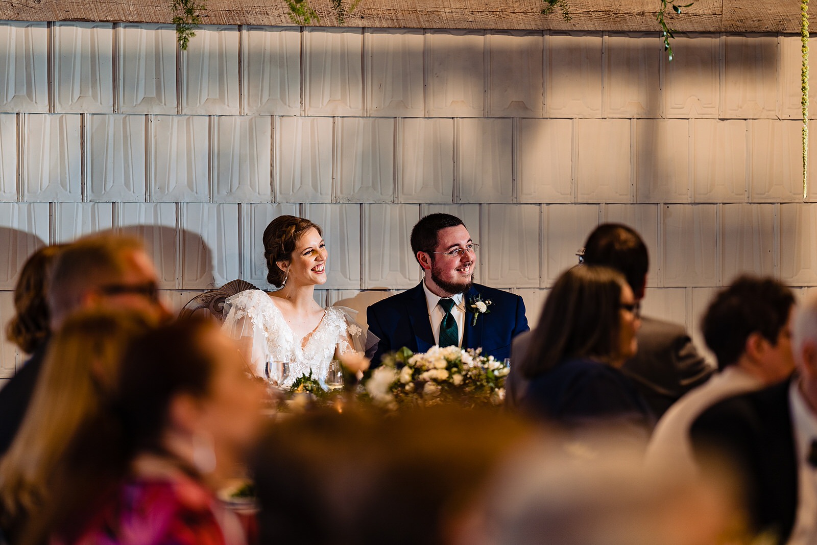 Bride and groom react to toasts from the sweetheart table at The Meadows Raleigh wedding reception