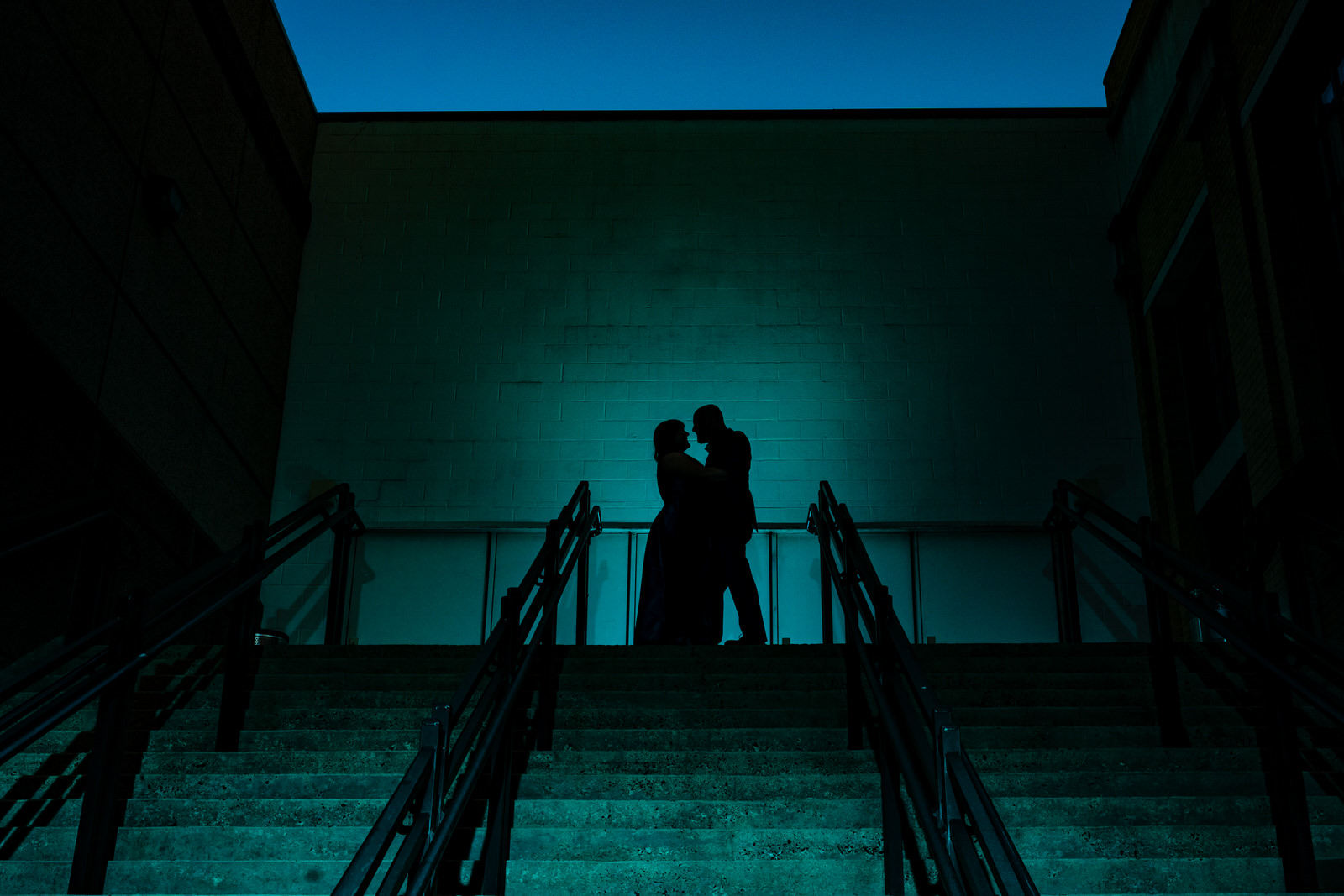 Silhouette of a man and a woman at the top of a staircase