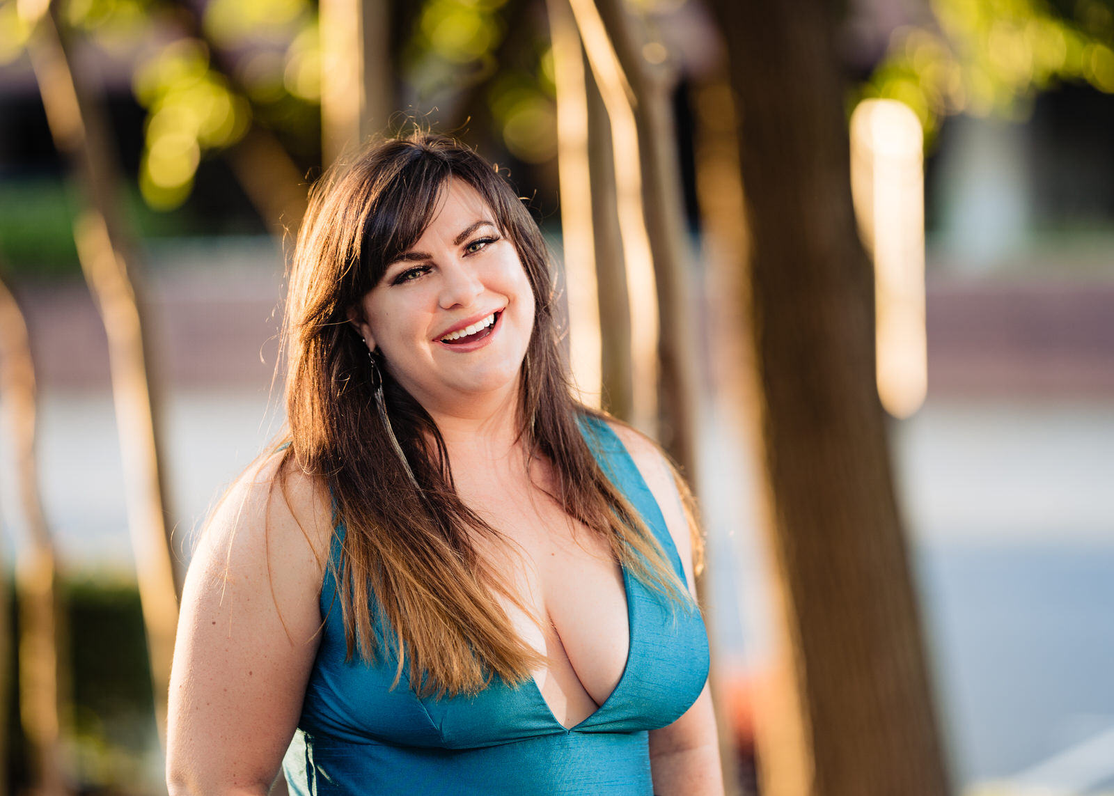 Woman in a teal dress laughing toward the camera