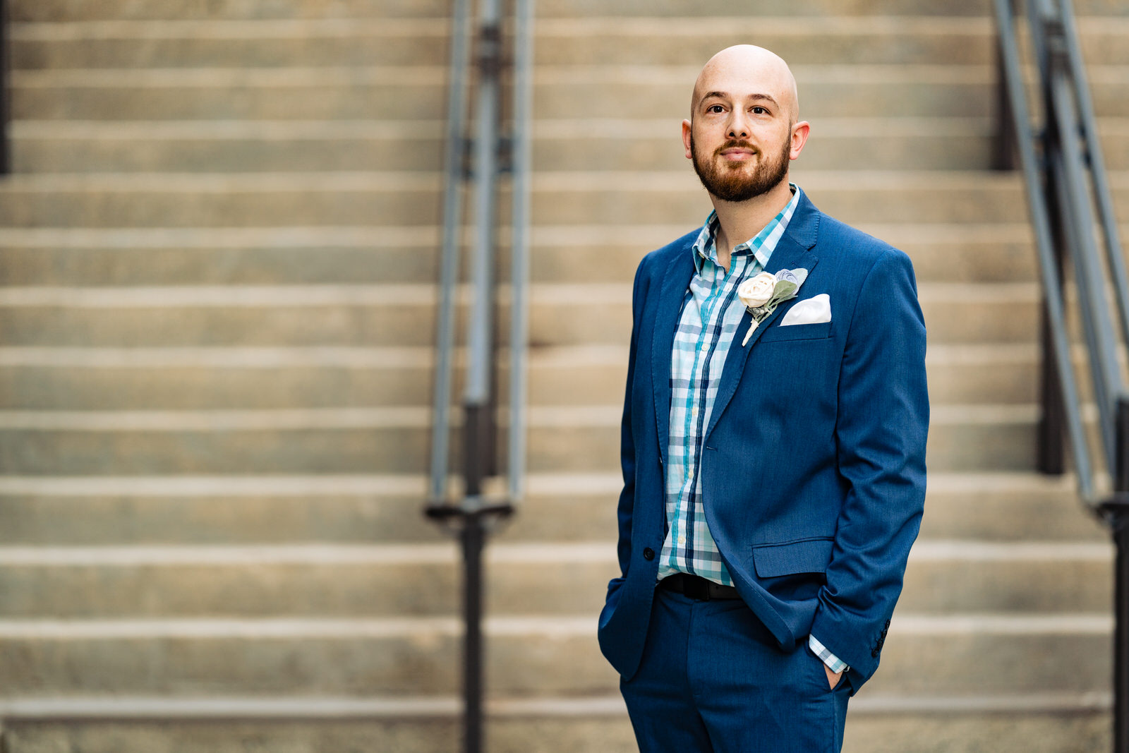 Man in a blue suit poses in front of a staircase for Durham Anniversary portraits