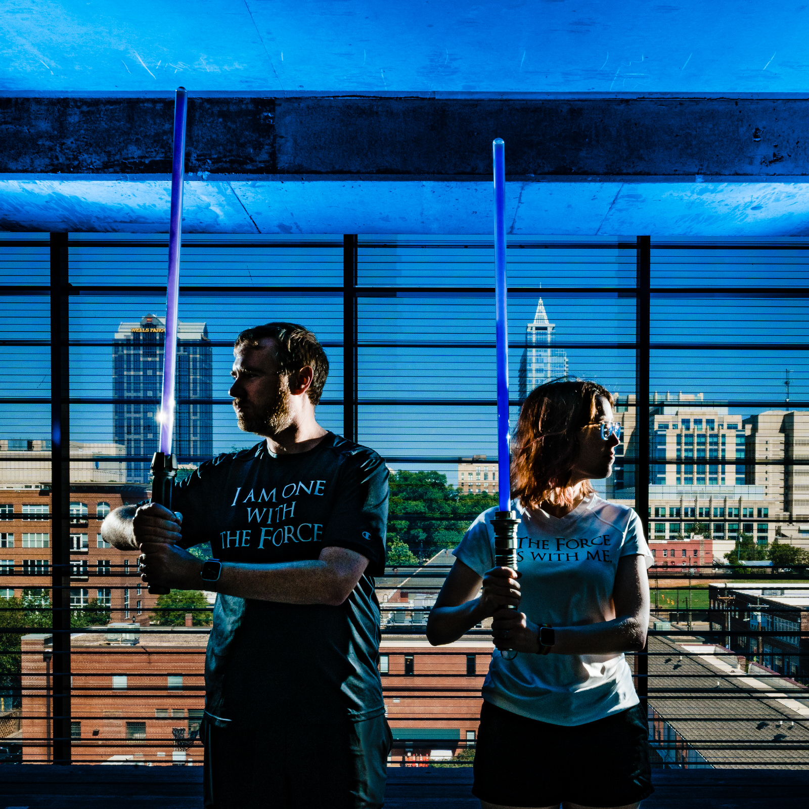Nerdy wedding photographers pose with lightsabers and the Raleigh skyline