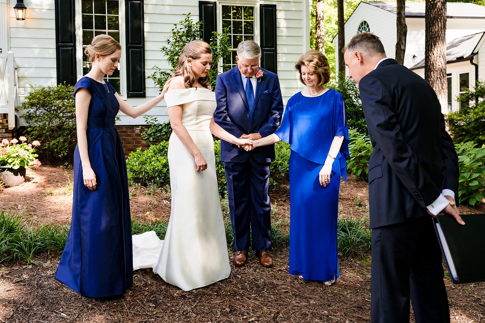 Bride and her family pray with the pastor before a Raleigh backyard wedding ceremony