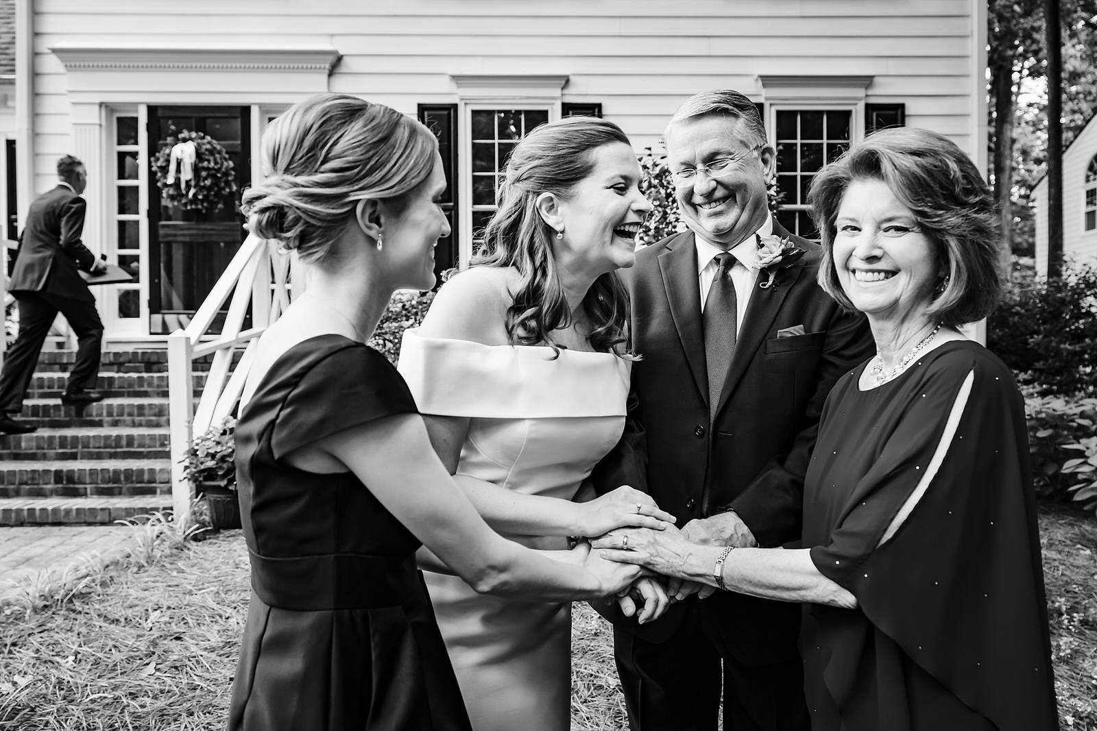 Bride and her family laugh and embrace before a Raleigh backyard wedding