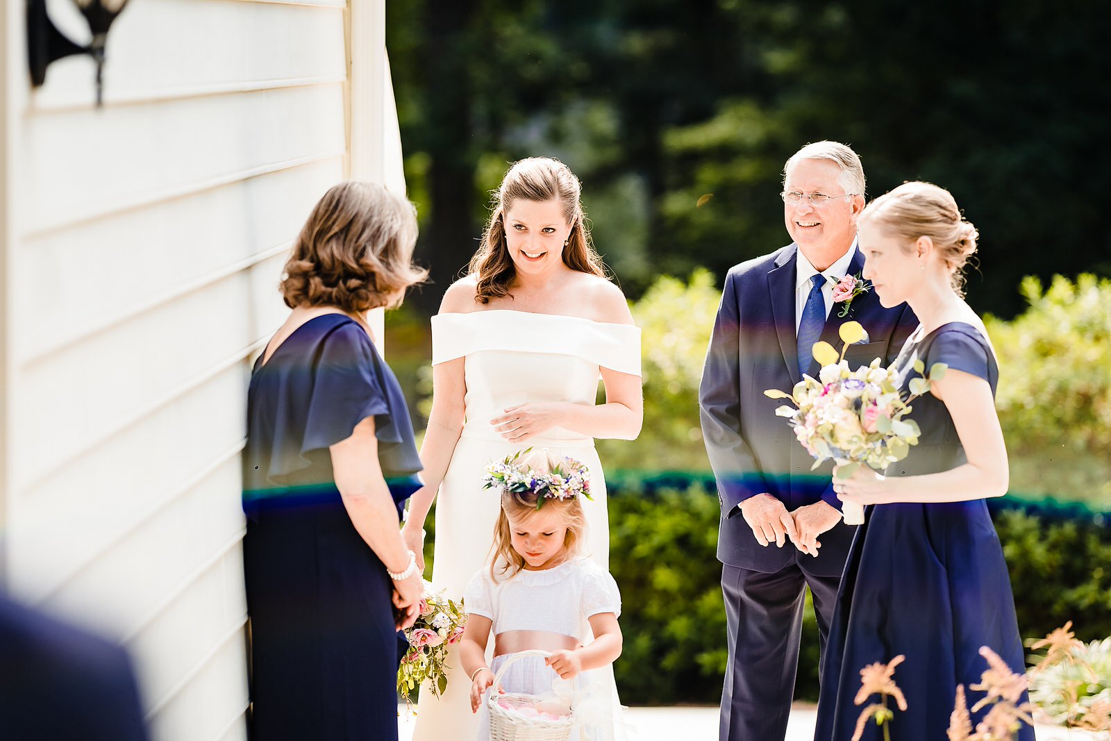 Bride waits with her father, sister, and flower girl before her backyard wedding ceremony starts