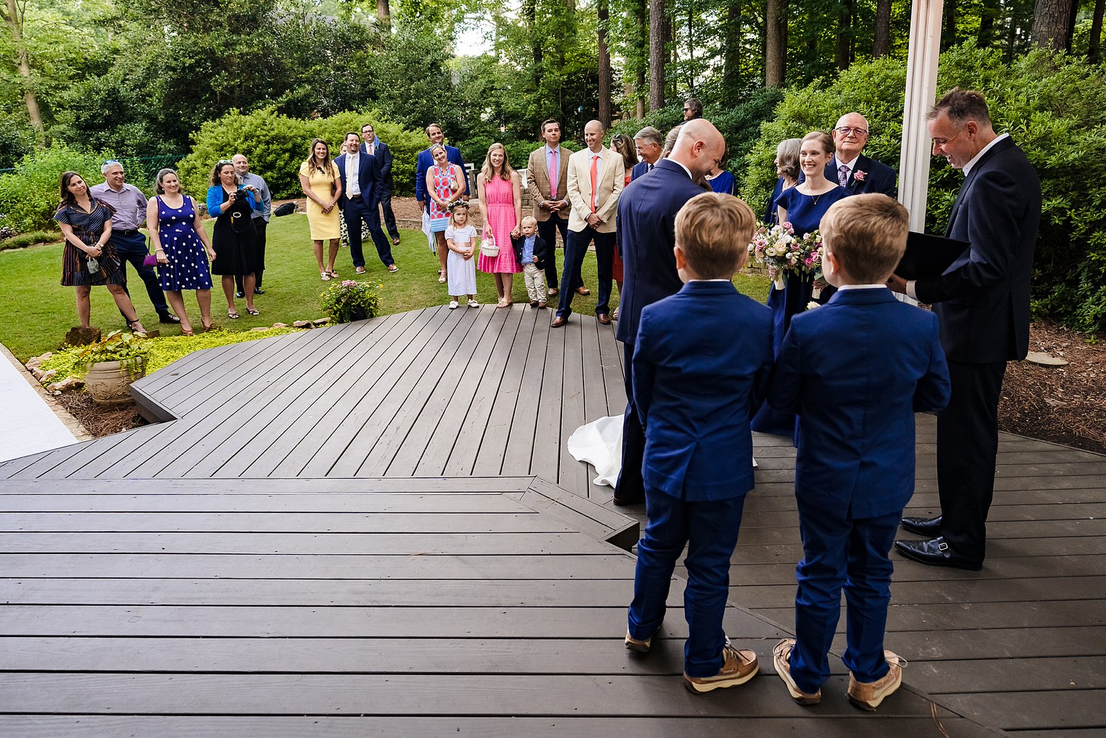 A group of friends and family stands in the backyard for a Raleigh wedding ceremony