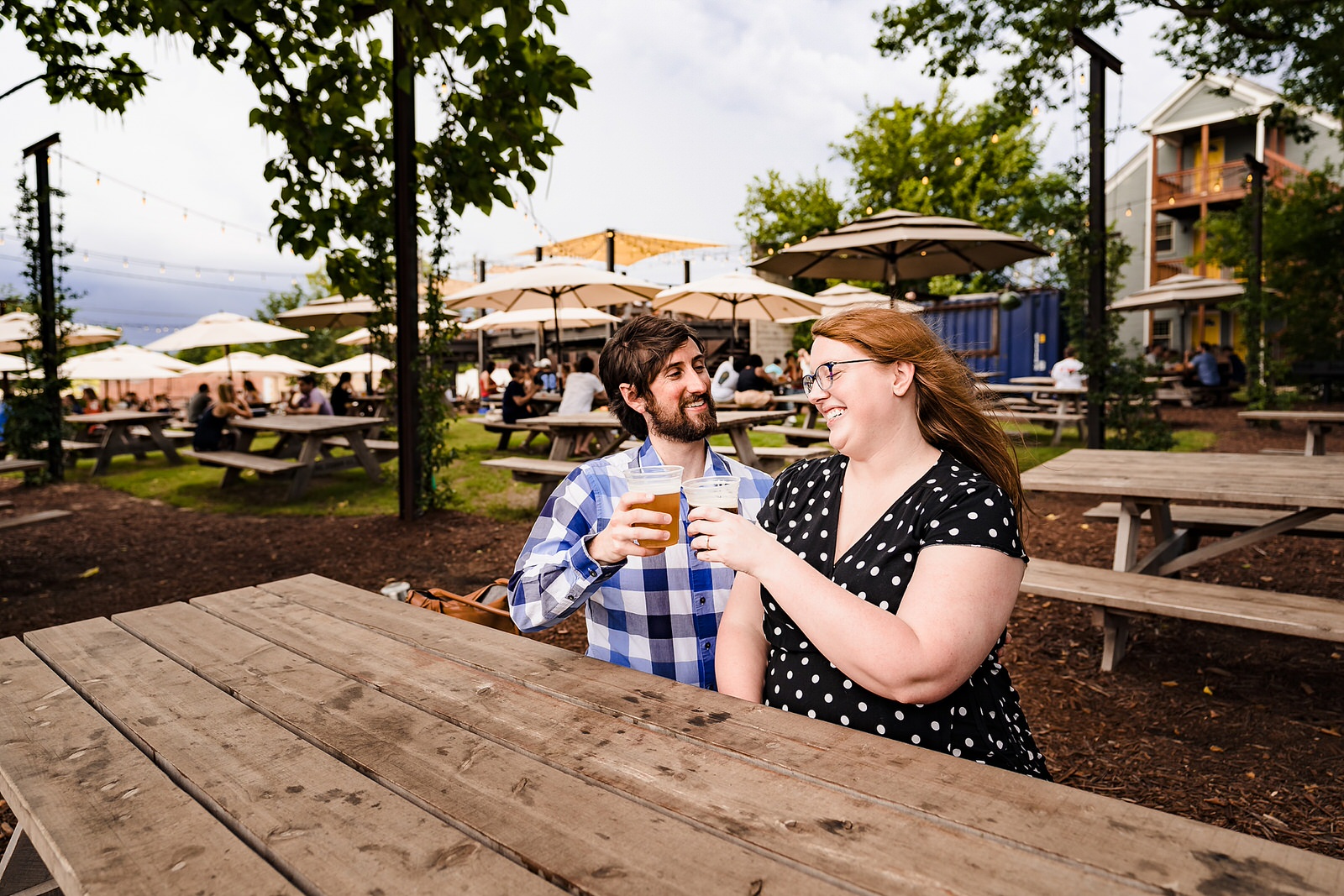 A couple toasts with their beer mugs at Ponysaurus during their engagement photo session