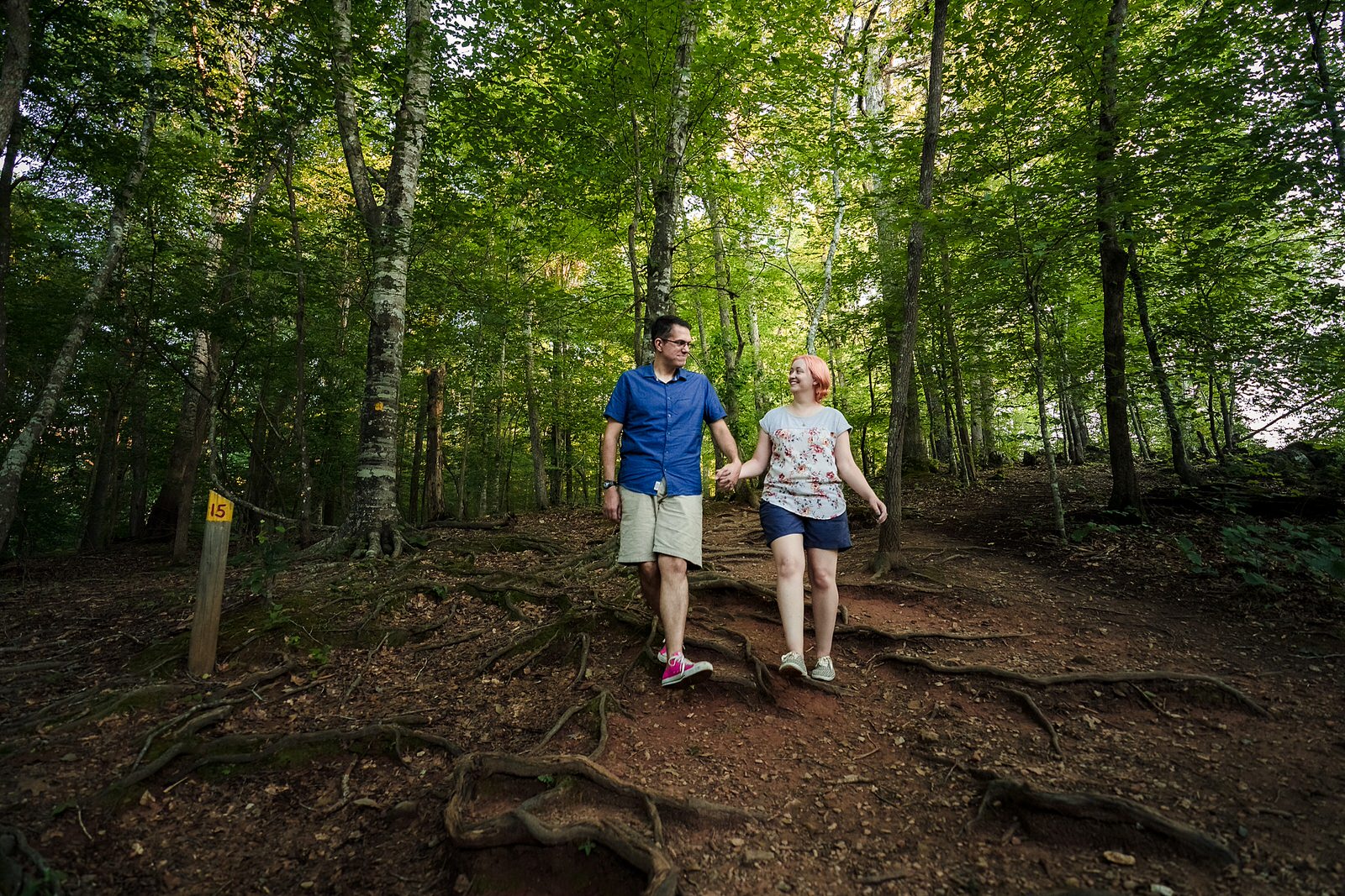 engaged couple hikes down a trail at West Point on the Eno River