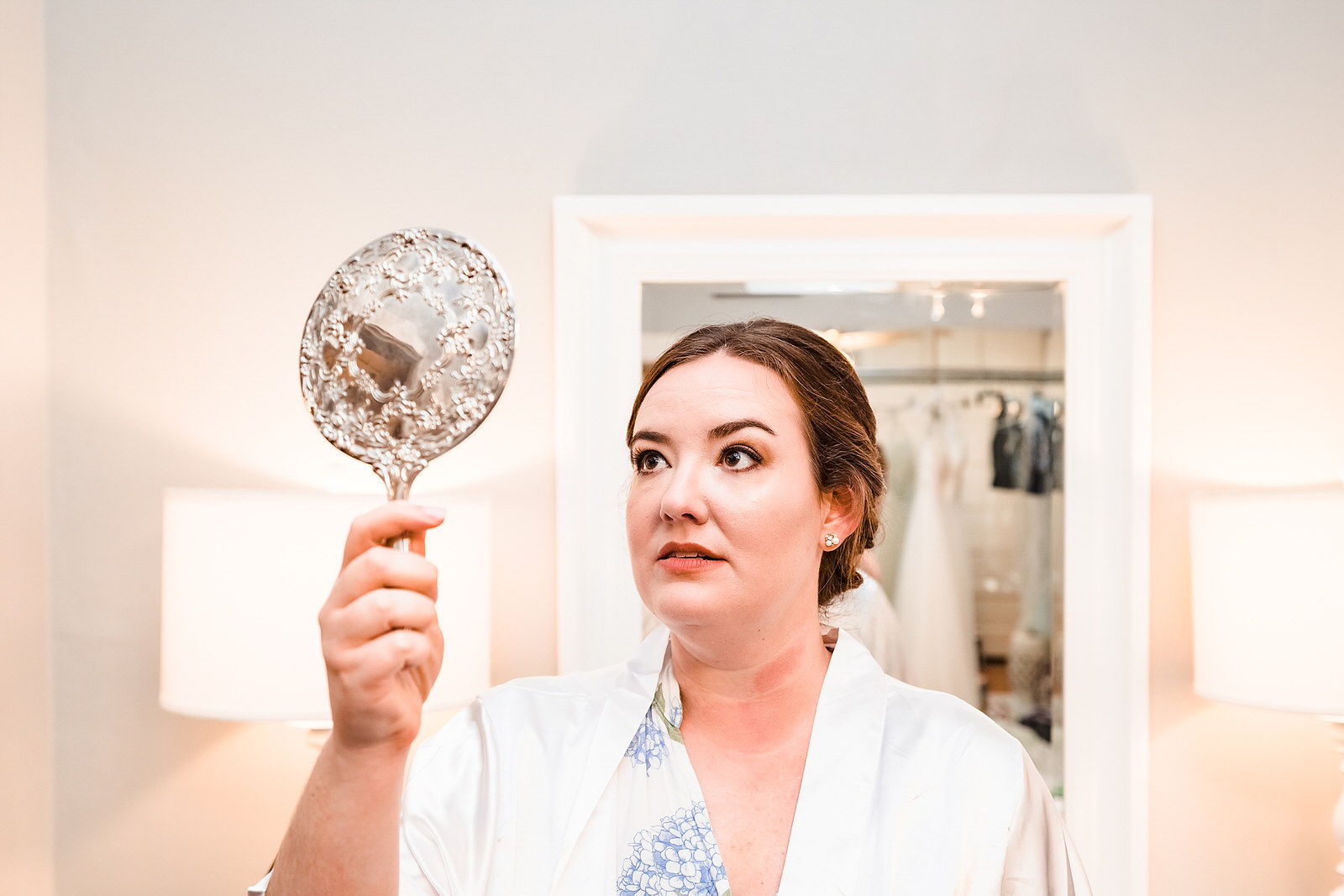 Bride checks out her reflection after finishing her hair and makeup on the morning of her wedding