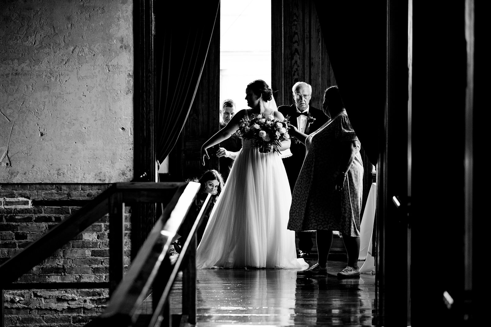 Wedding planner helps bride and her father get into their final position for wedding ceremony processional
