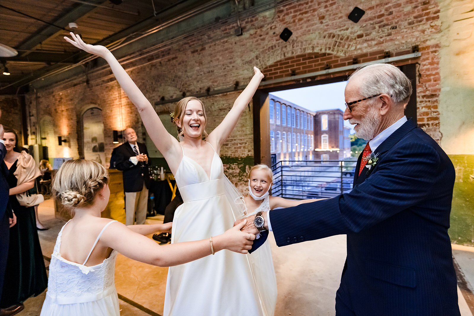 Bride's father and her nieces dance with her at wedding reception