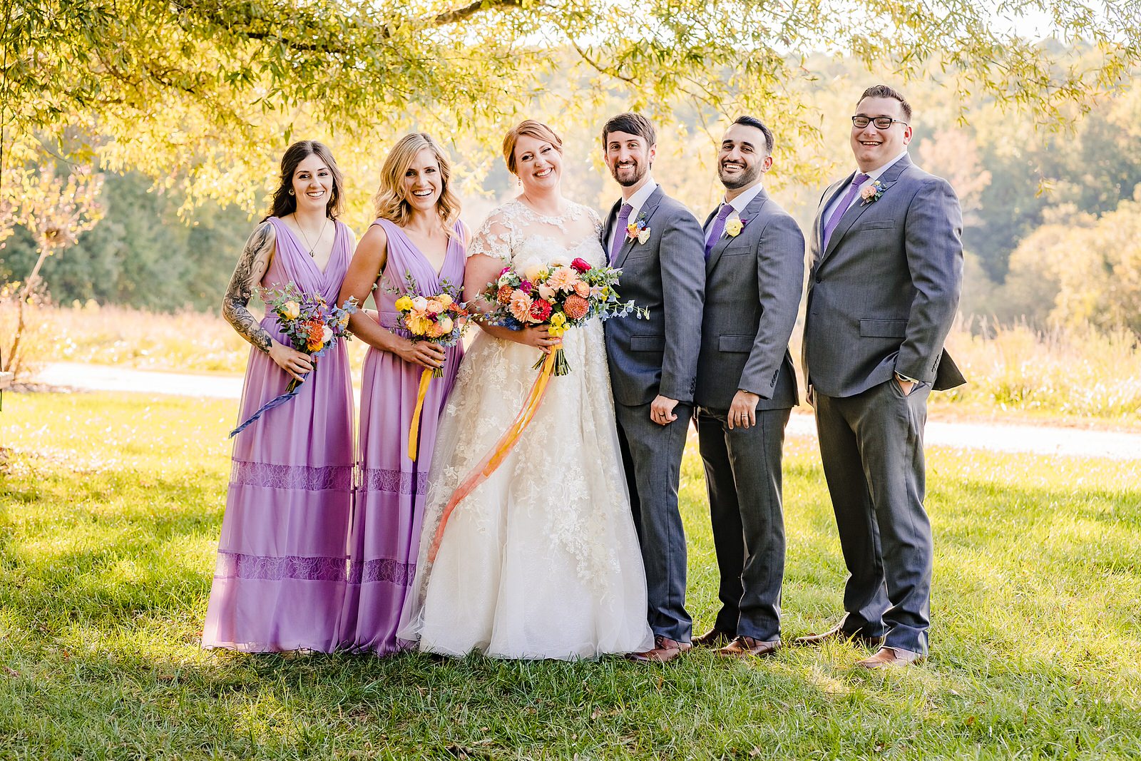 Wedding party style: lavendar bridesmaid dresses, grey suits, colorful bouquets of wildflowers