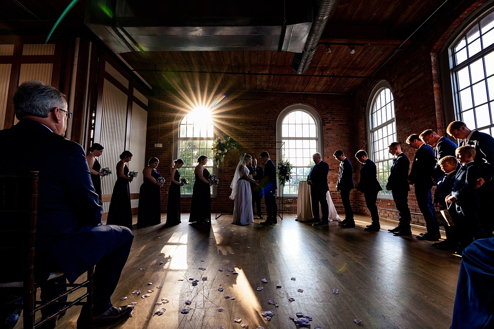 the sun pokes through one of The Cotton Room's large windows during a wedding ceremony