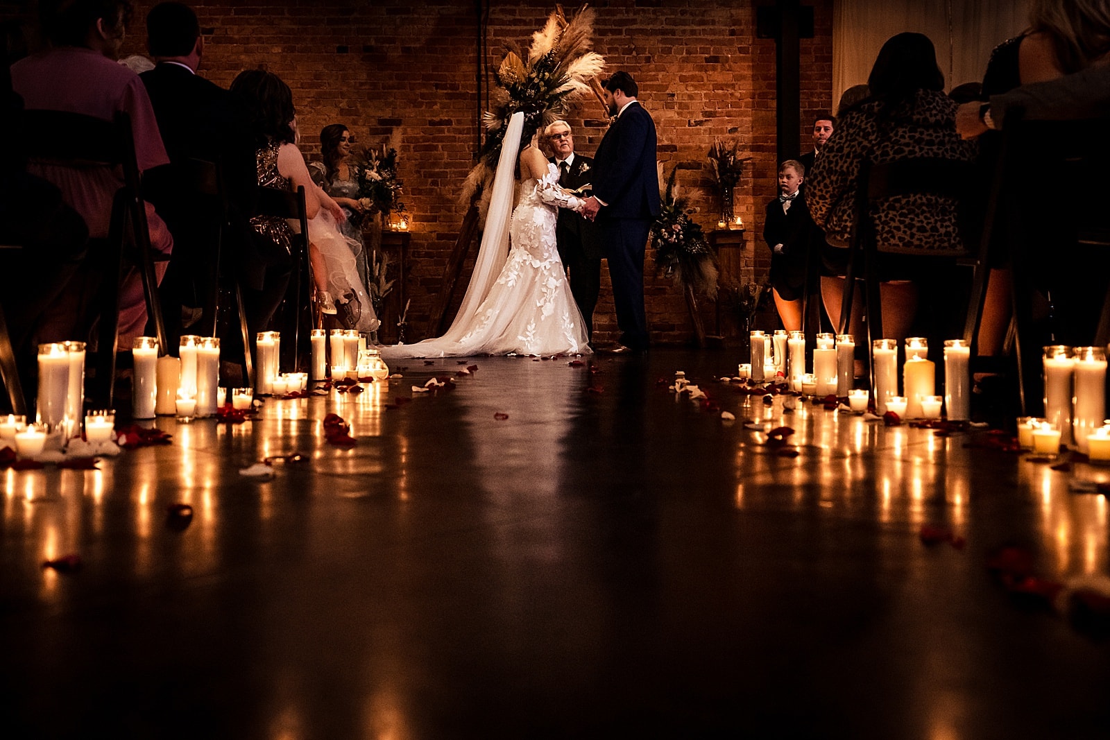 candle-lit wedding ceremony at Brick & Mortar events with backdrop made by friends and family of the couple