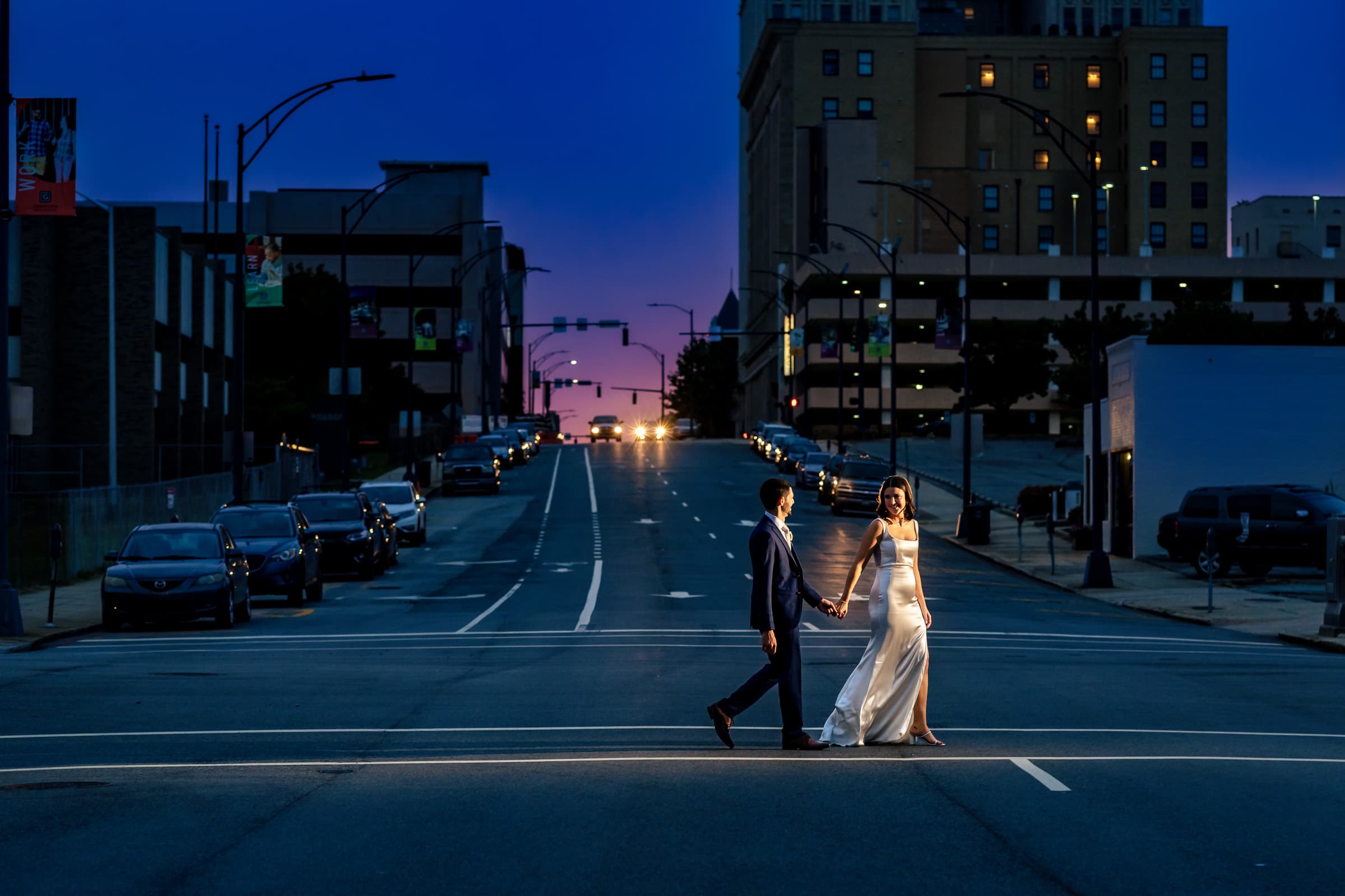 couple in wedding attire walks hand in hand through downtown Greensboro, NC