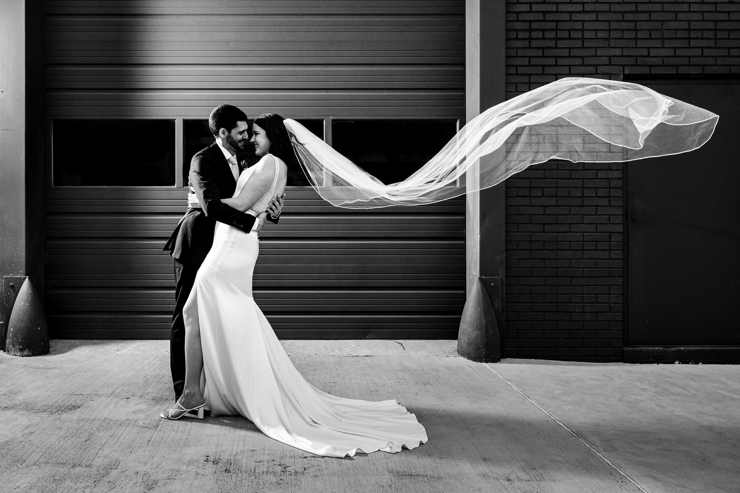 Newlywed couple embraces as the bride's veil is swept back | photos by Kivus & Camera