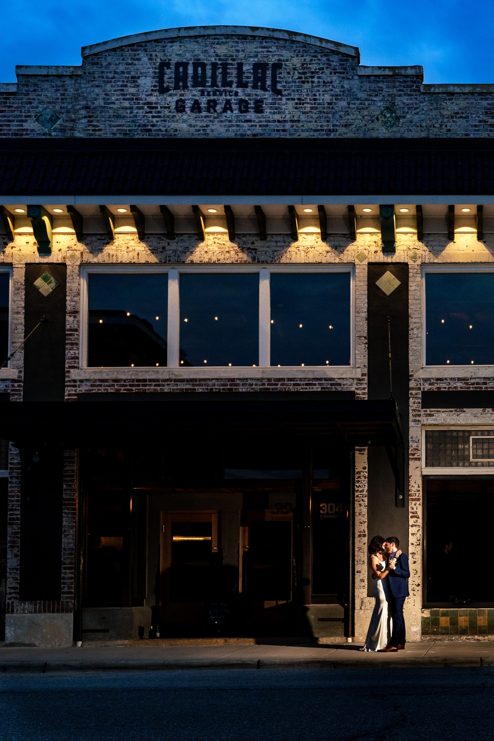 Newlywed couple embraces in front of the Cadillac Service Garage wedding venue | photos by Kivus & Camera