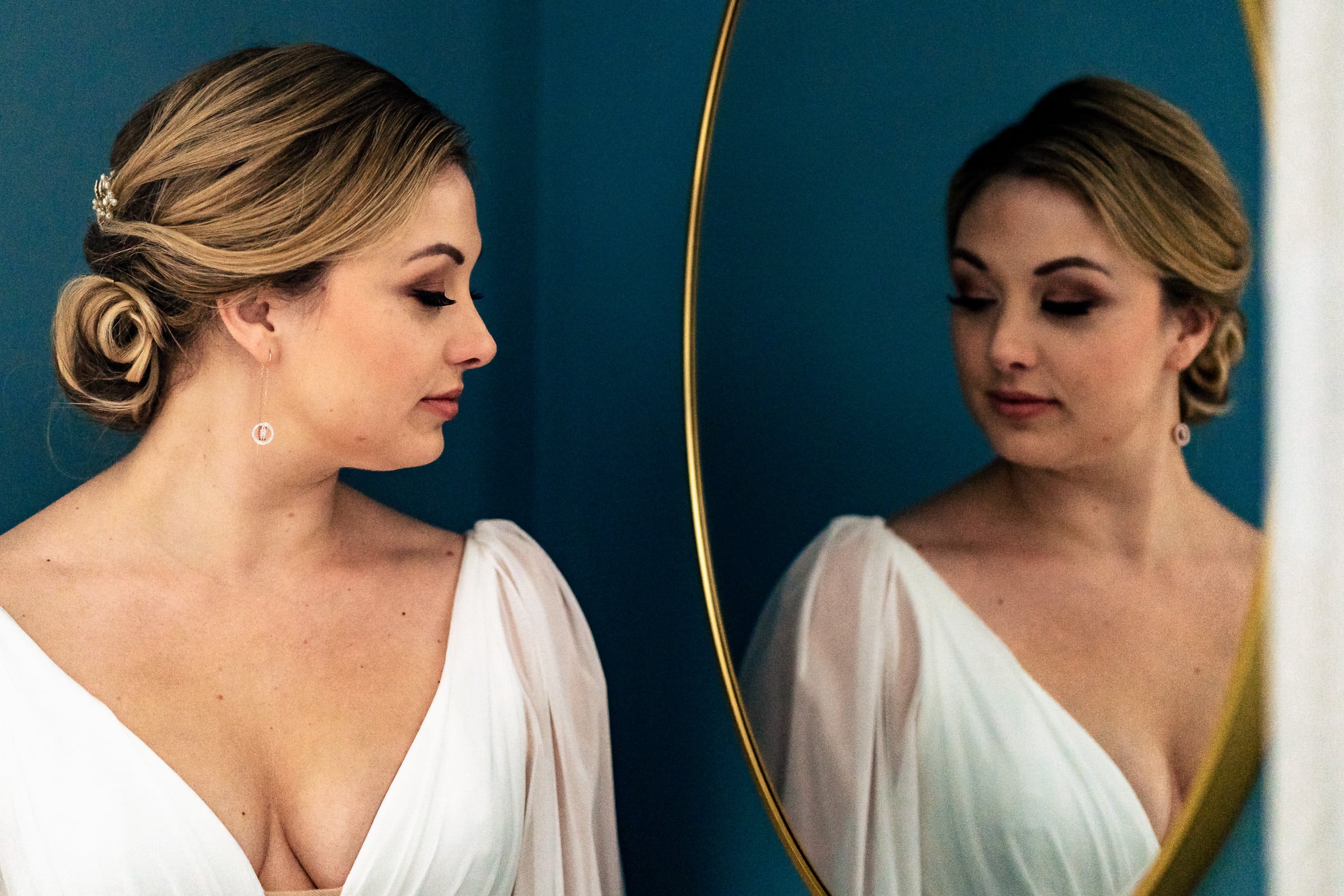 bride in long sleeved wedding dress looks at herself in the mirror | photos by Kivus & Camera