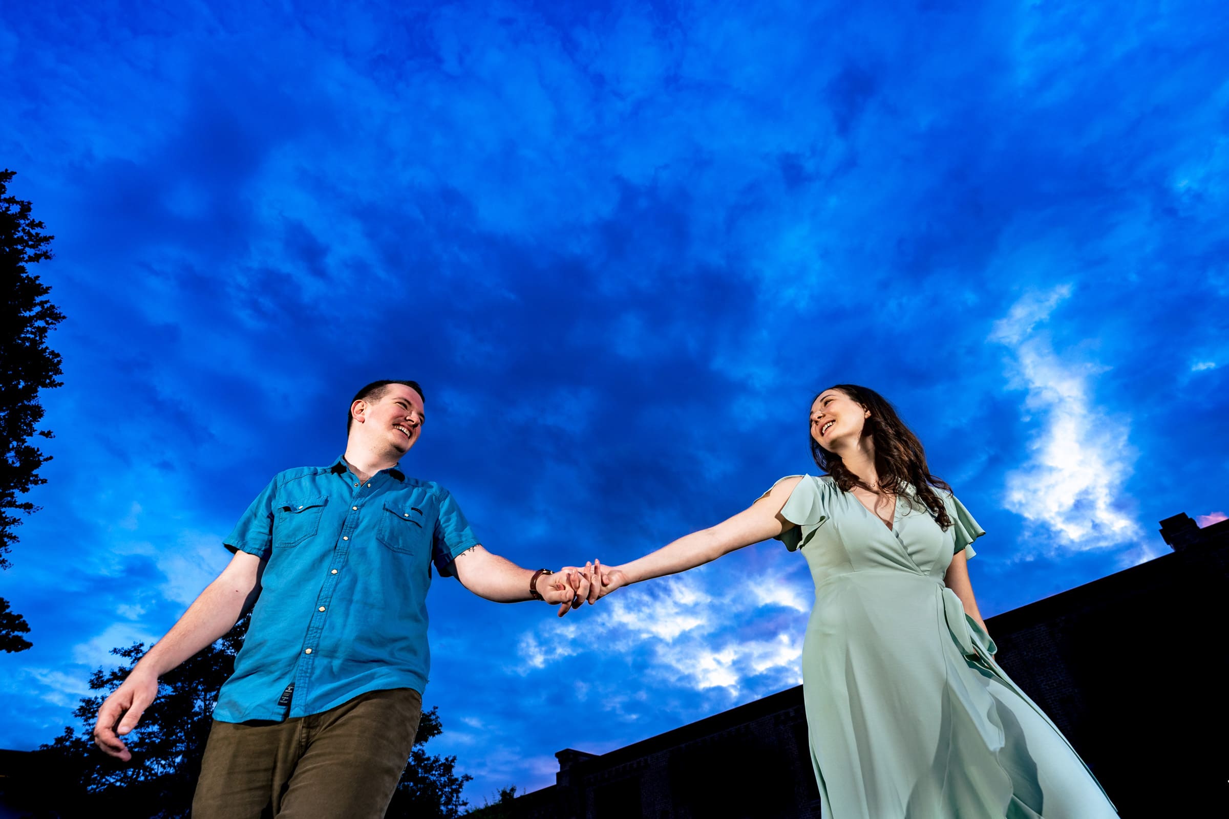 dramatic blue sky portrait of a couple during their engagement photos at American Tobacco Campus