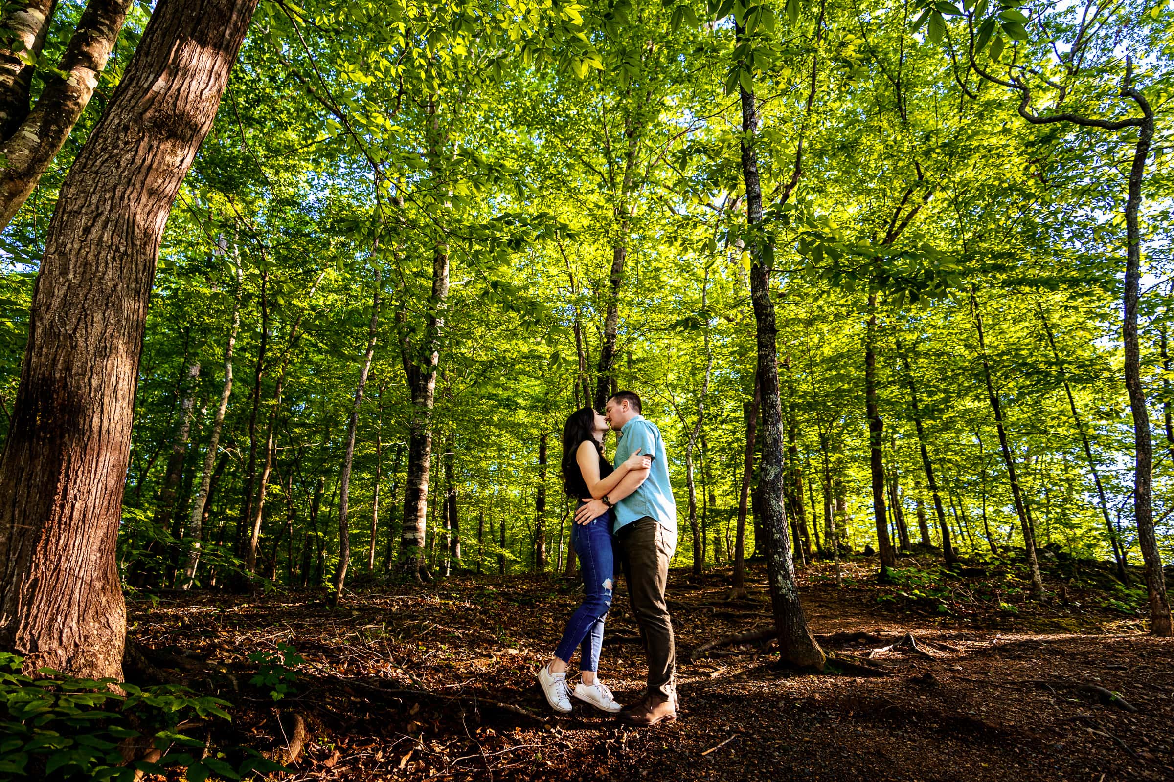 Couple embraces in the middle of a bright green, forested area at West Point on the Eno | photo by Kivus & Camera