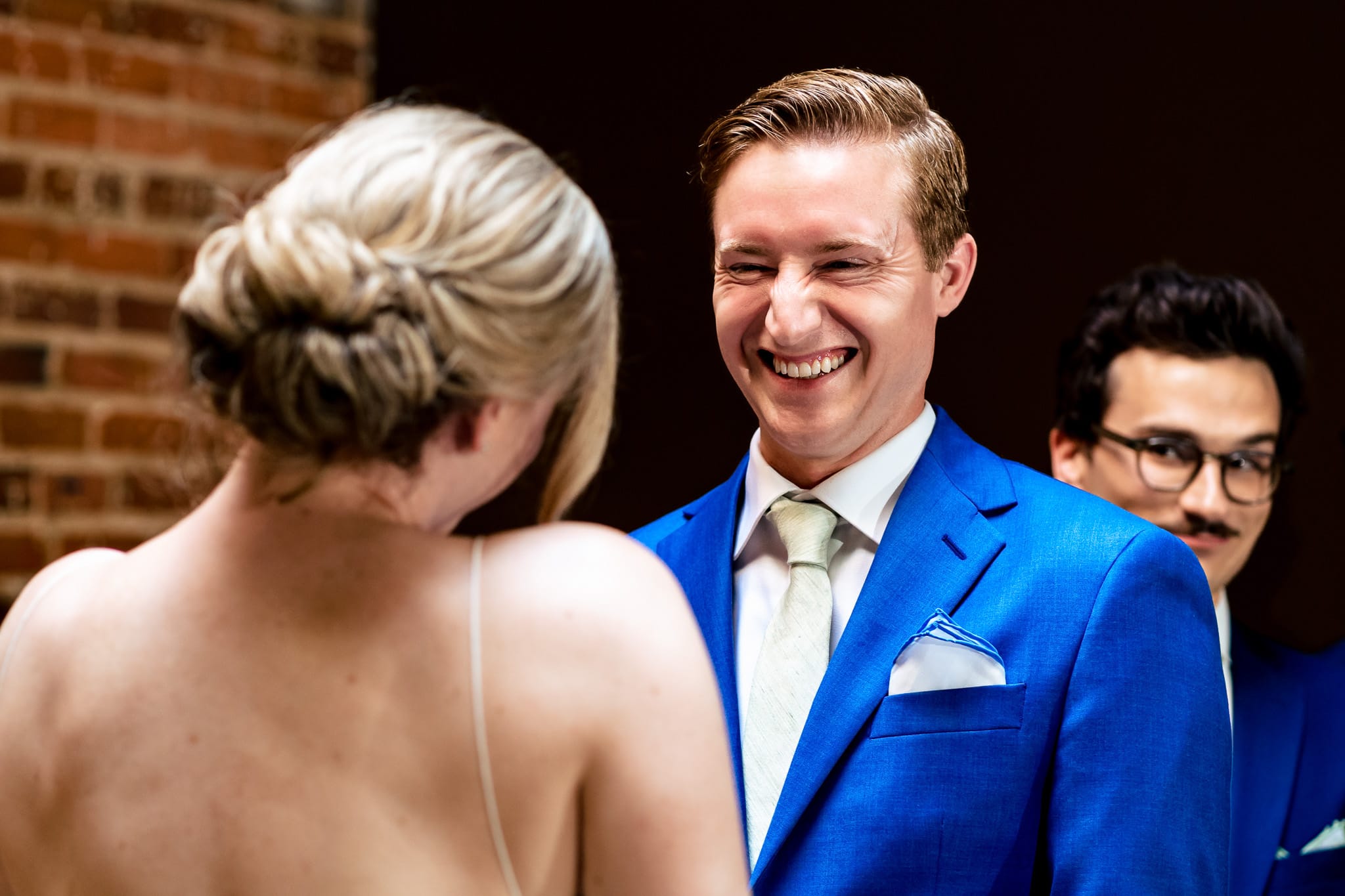 groom laughs during indoor wedding ceremony at The Grove at City Market | photo by Kivus & Camera