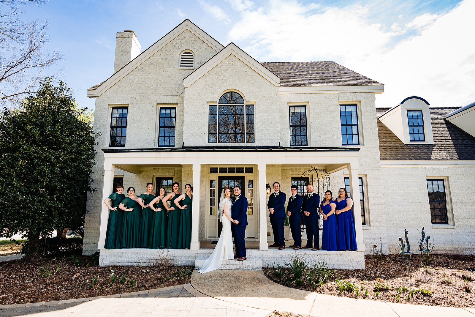 Wedding party poses for a portrait at The Meadows Raleigh in green and blue dresses and blue suits