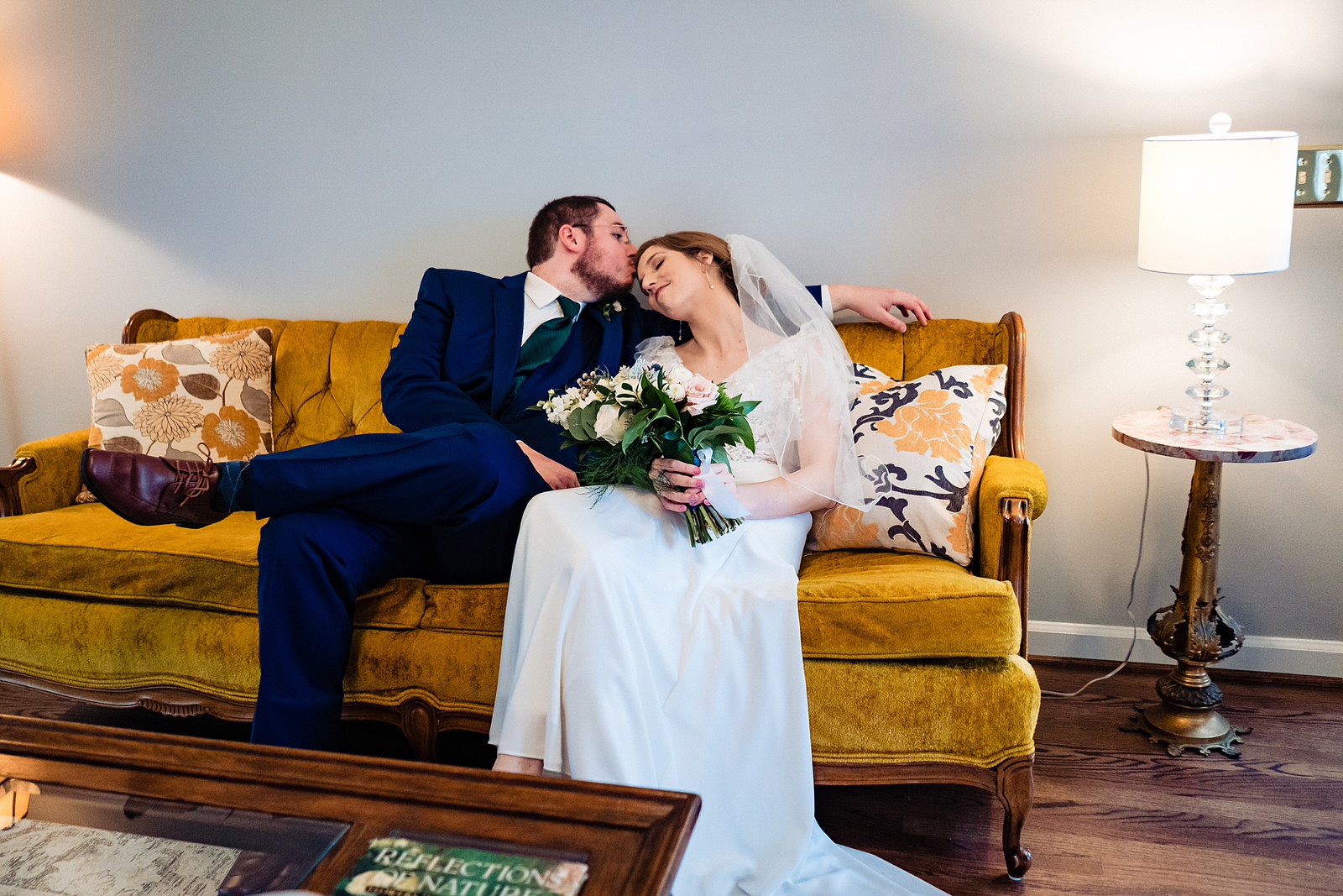 Bride & groom snuggle on a couch in the moments after their wedding ceremony at The Meadows Raleigh