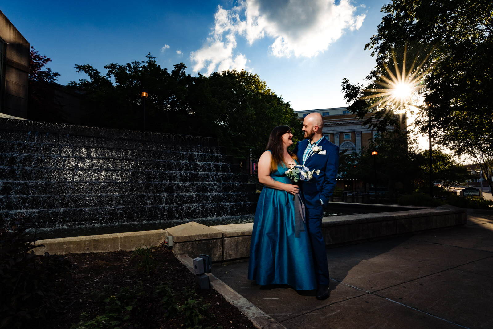 Couple poses in front of the waterfall next to the Durham Convention Center