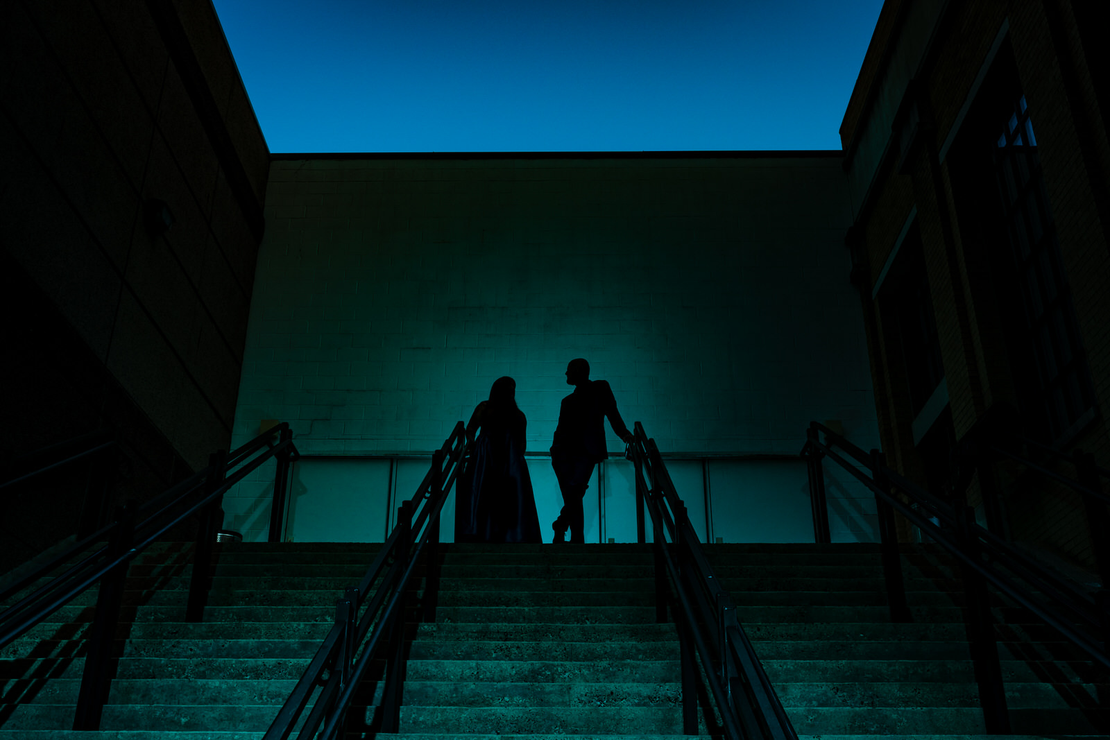 Silhouette of a man and a woman at the top of a staircase