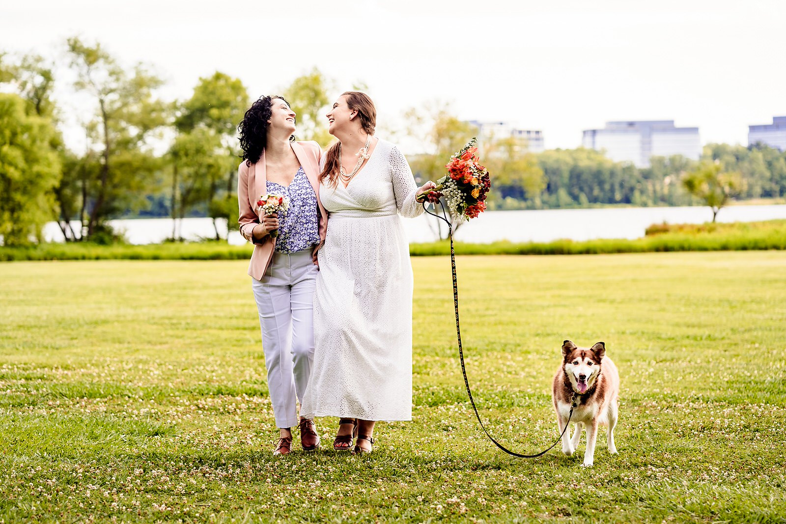 two brides walking with their dog and colorful wedding bouquets