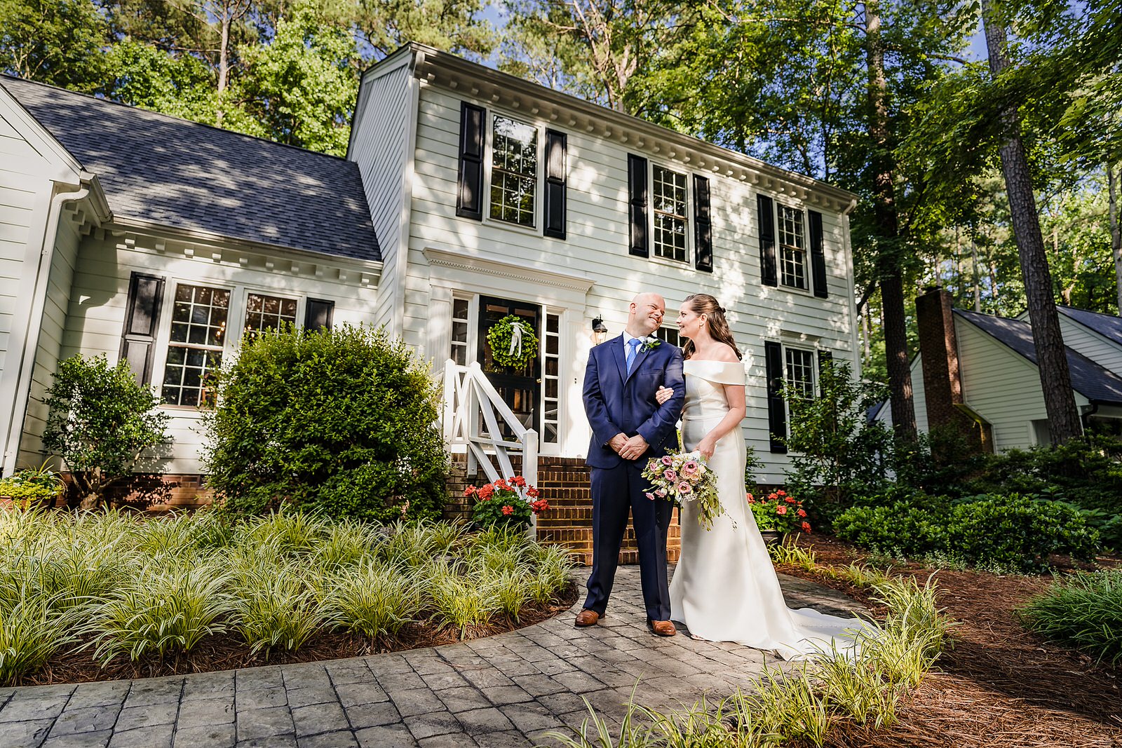 Bride and groom stand in front of their house in North Raleigh