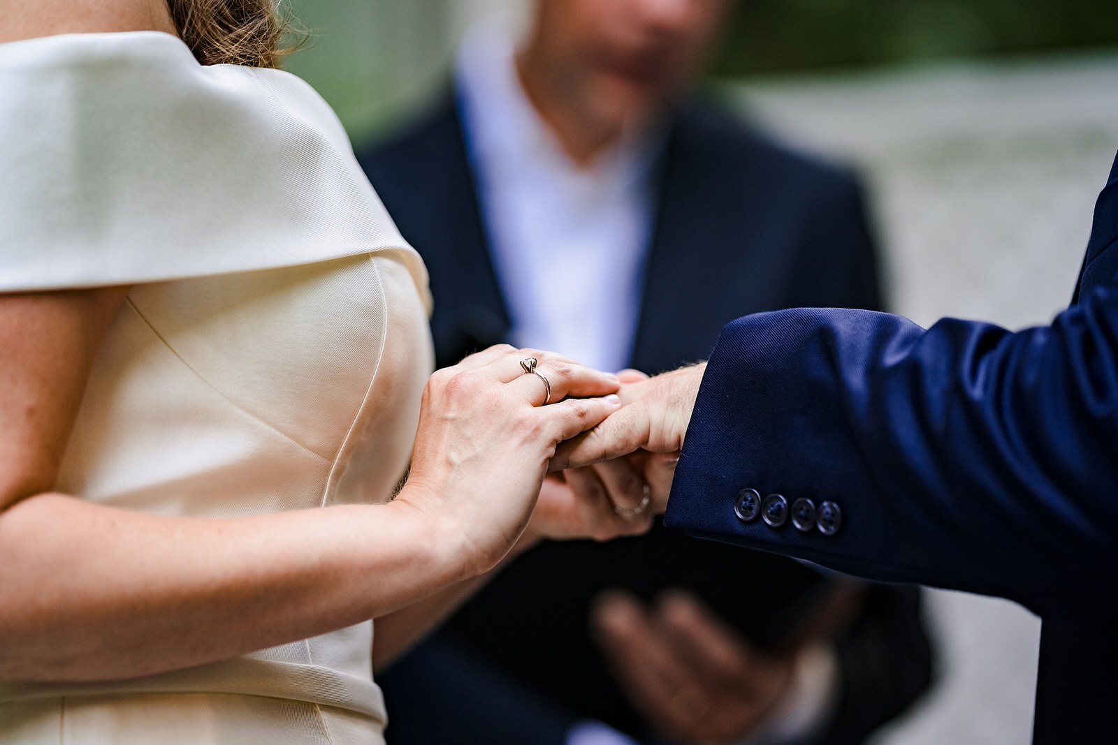 Bride slides wedding ring onto groom's finger