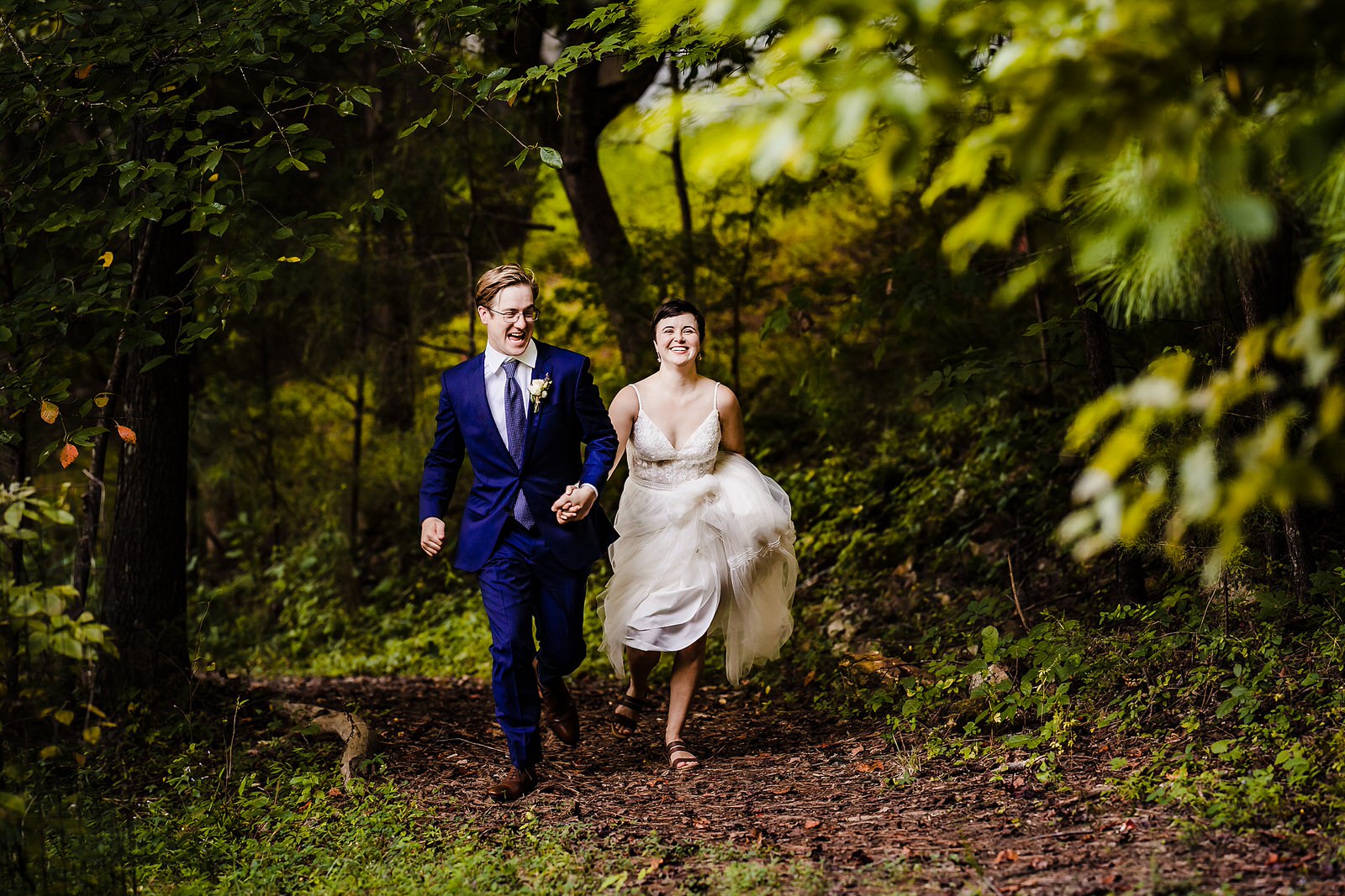 Bride and groom laugh as they run through a wooded area during their Chapel Hill Elopement