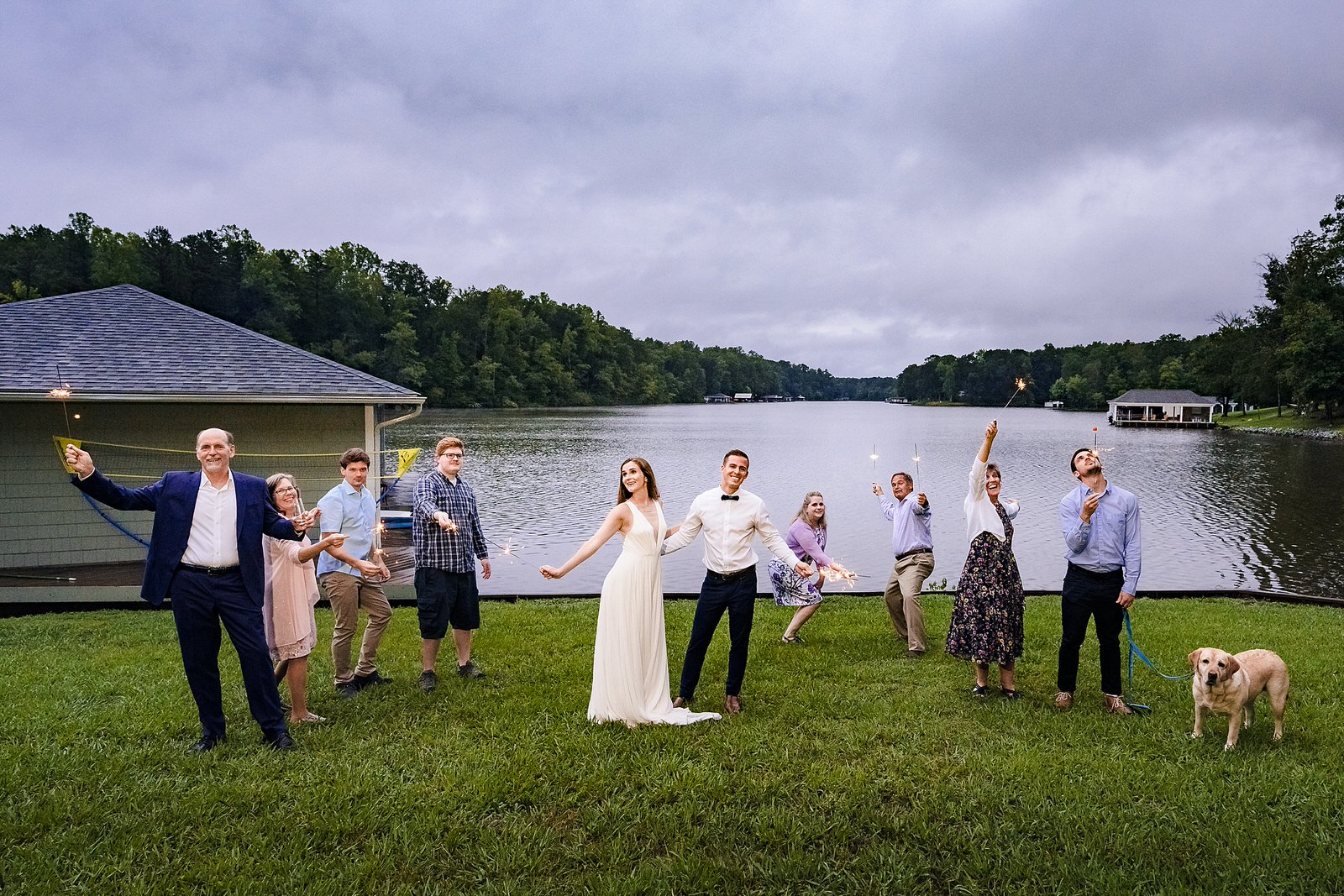 Wedding party poses with sparklers in front of a lake