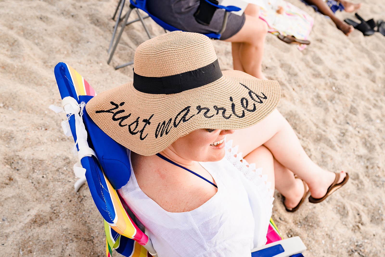 Bride wears a just married hat at the beach at her casual wedding reception