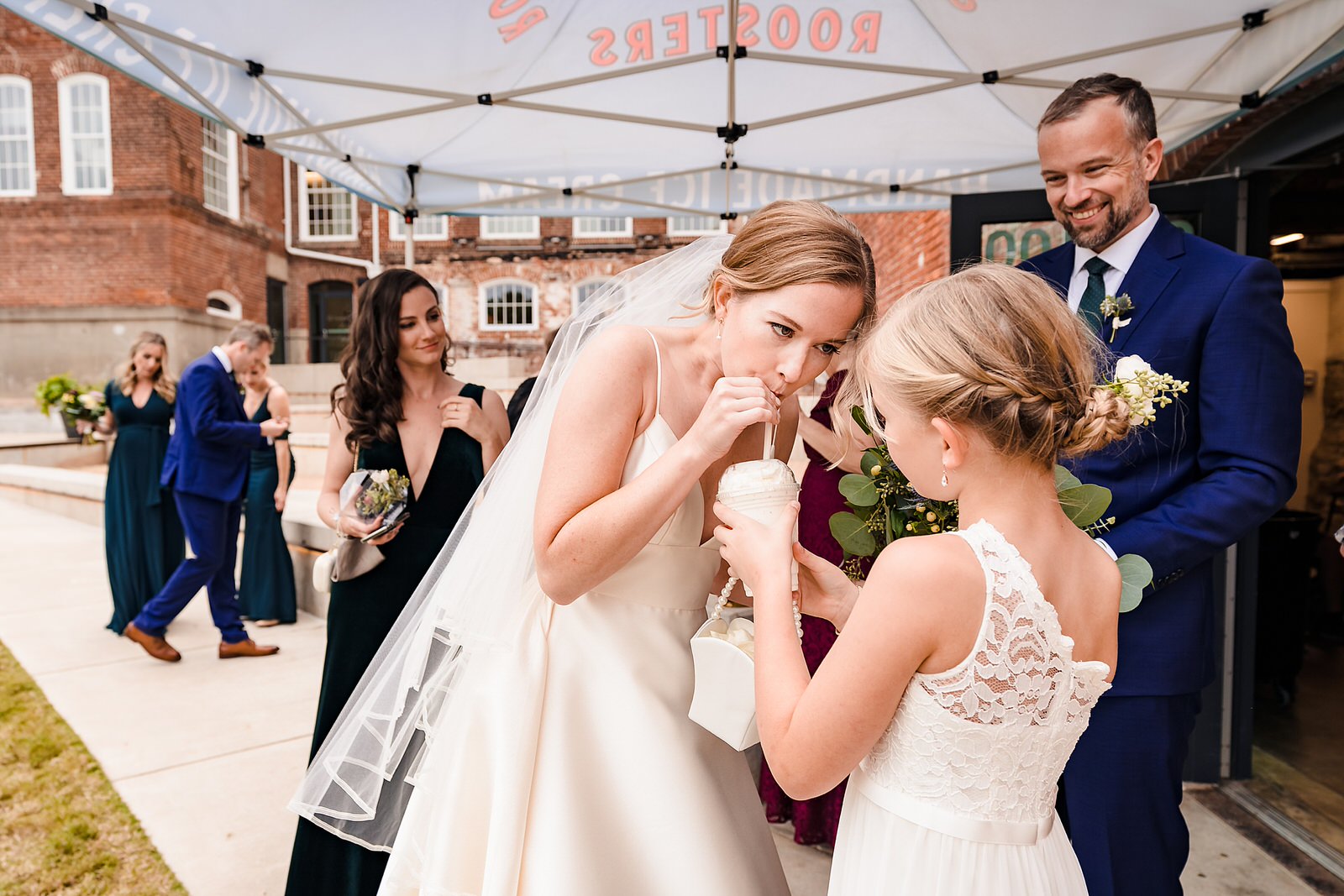 Bride takes a break to have some of the flower girl's milkshake before the ceremony