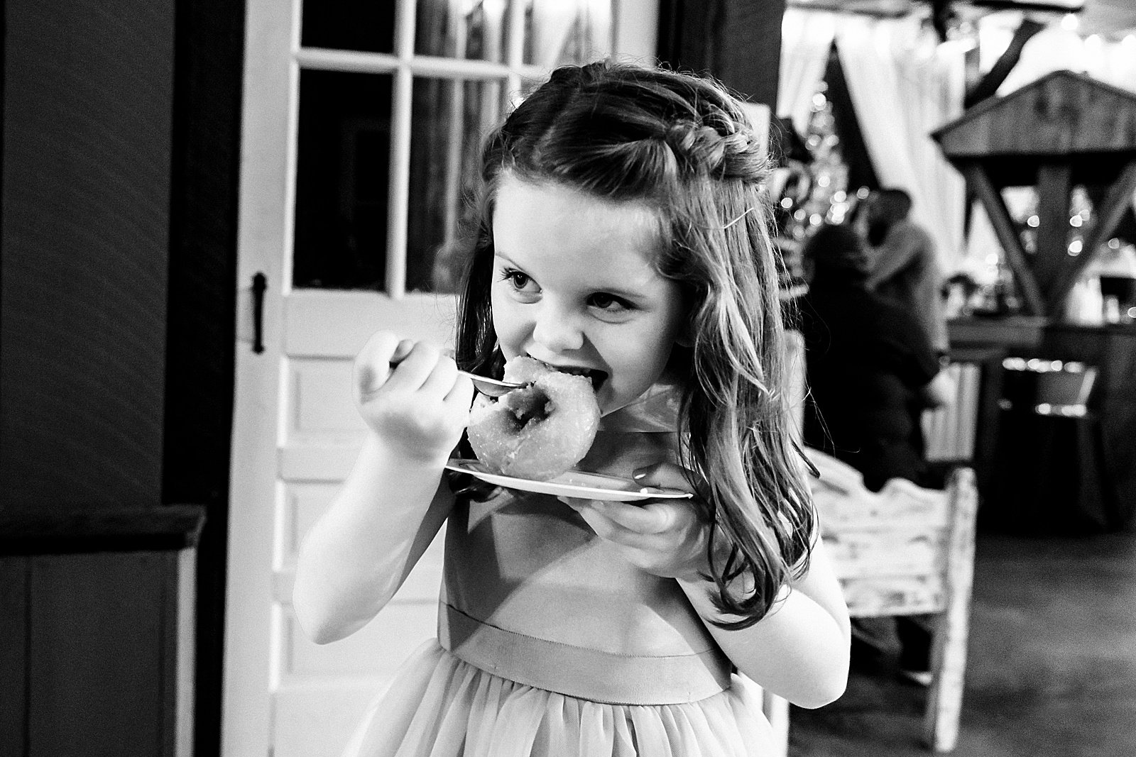flower girl chows down on a donut from the wedding dessert table