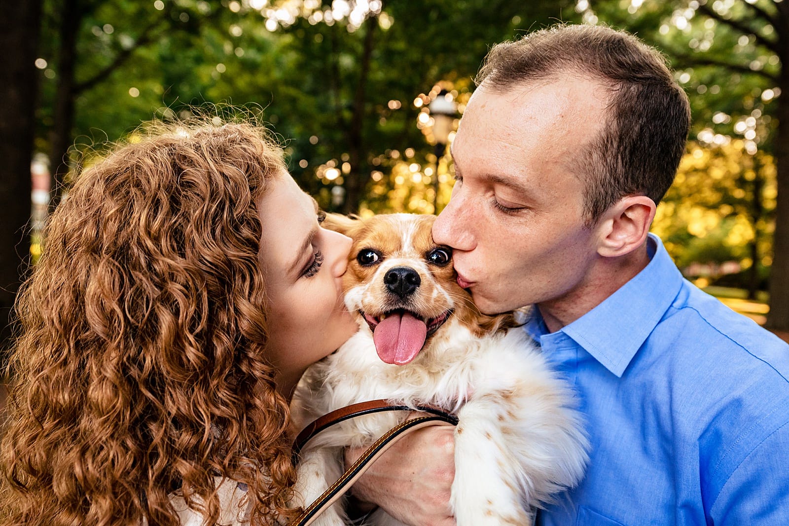 man and woman hold a dog between them and kiss its cheeks