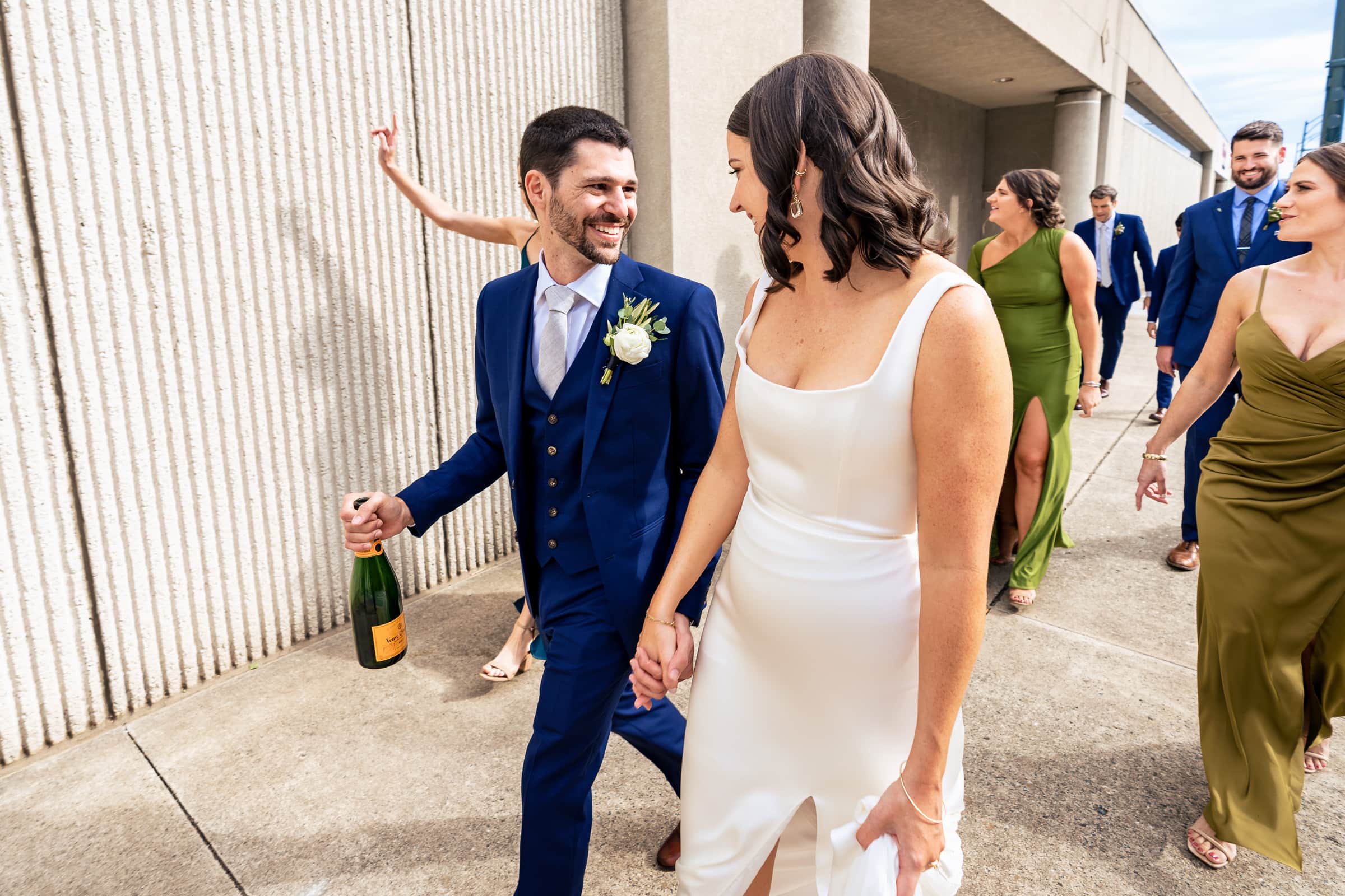bride and groom walk down the street with their wedding party | photos by Kivus & Camera