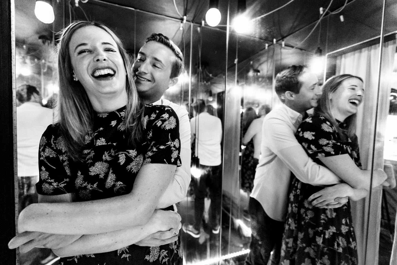A couple laughs with their reflections all around them, in a small room full of mirrors creative engagement photography at Killjoy Cocktail bar in Raleigh, NC | photos by Kivus & Camera