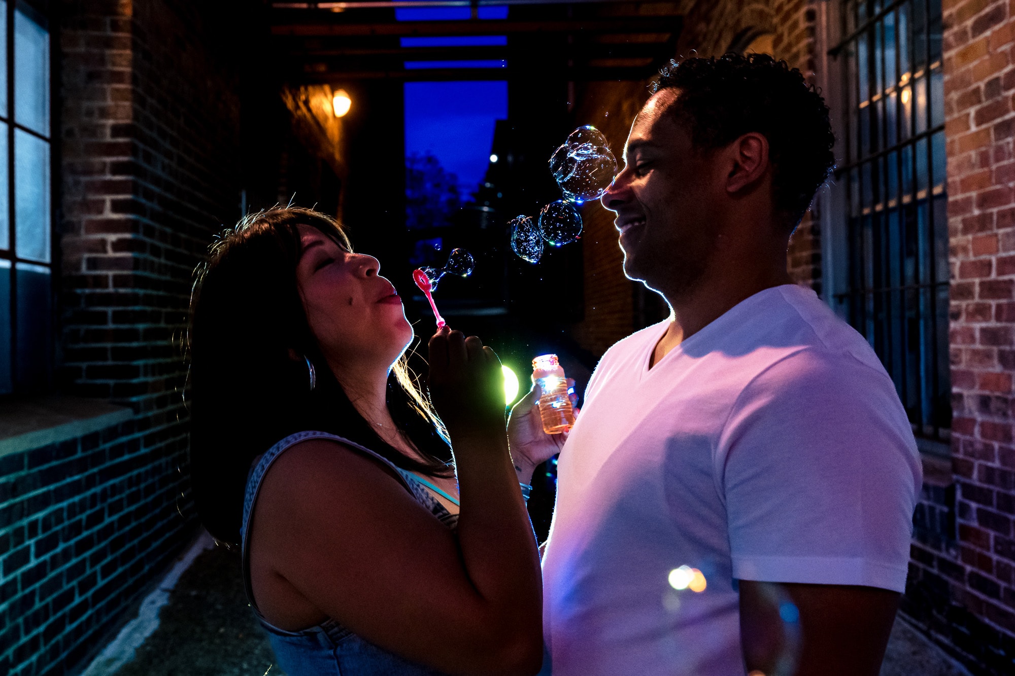 blue hour portraits of a man and woman laughing and blowing bubbles
