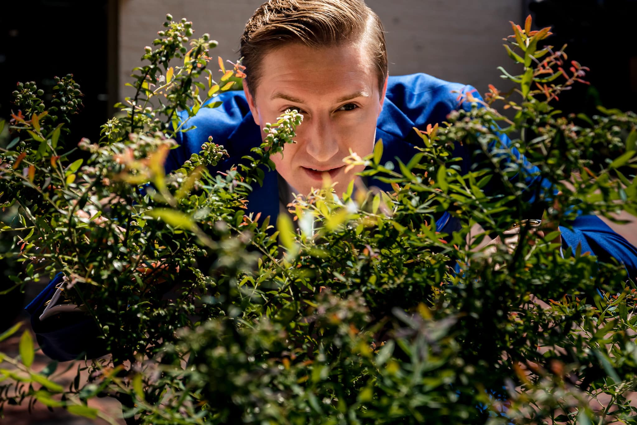 groom "hides" behind a bush after suggesting he jump out to scare the bride for the first look | photo by Kivus & Camera