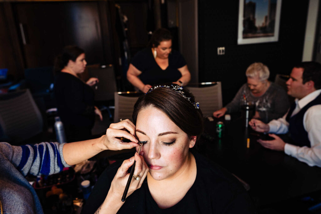 wedding makeup artist from Wink Hair & Makeup applies false eyelashes for a bride | photo by Kivus & Camera