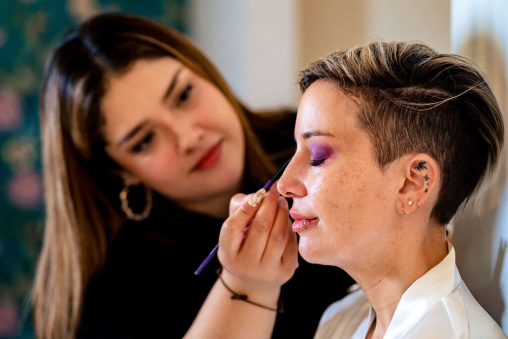 makeup artist from The Makeup Addict applies purple eyeshadow to a bride for her wedding in downtown Raleigh | photo by Kivus & Camera