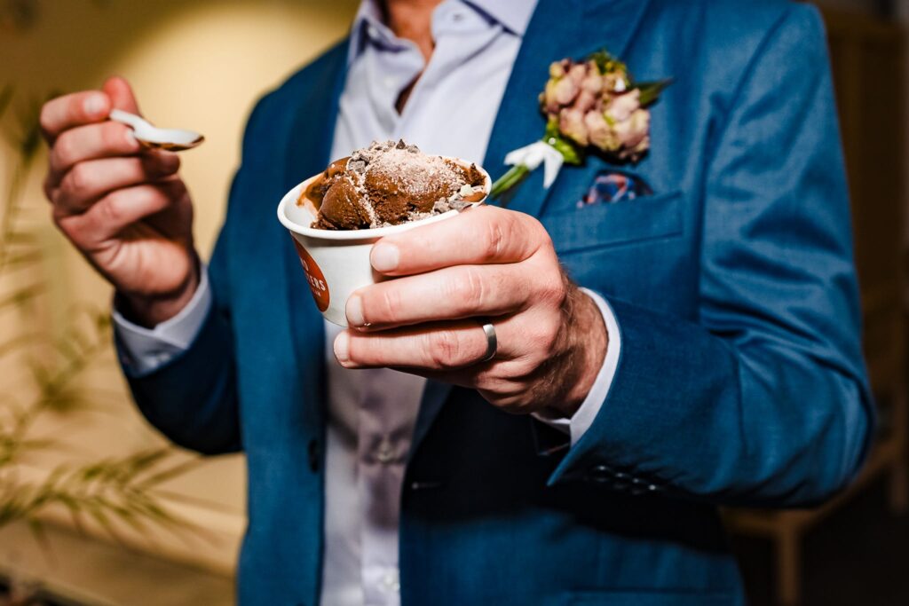 at a wedding reception, the groom holds a cup of chocolate ice cream from Two Roosters - ice cream makes a great wedding dessert | photo by Kivus & Camera