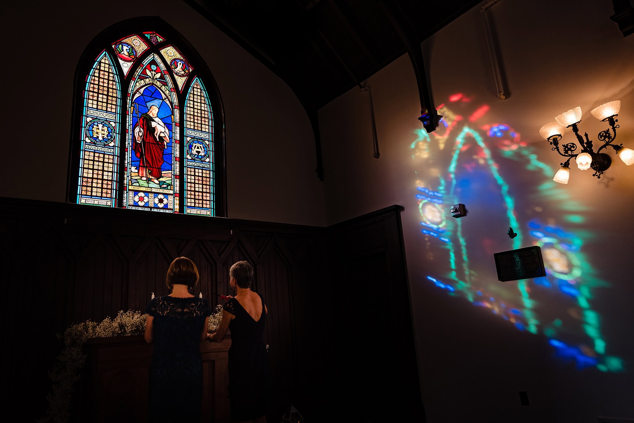 Mother of the bride and mother of the groom light candles on the altar at All Saints Chapel for a wedding ceremony