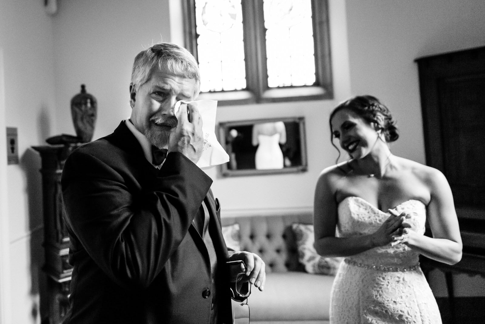 father of the bride wipes tears from his eyes after his first look with her
